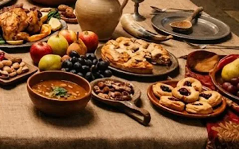 Apples, grapes and small pastries beside a bowl of soup on a feast table