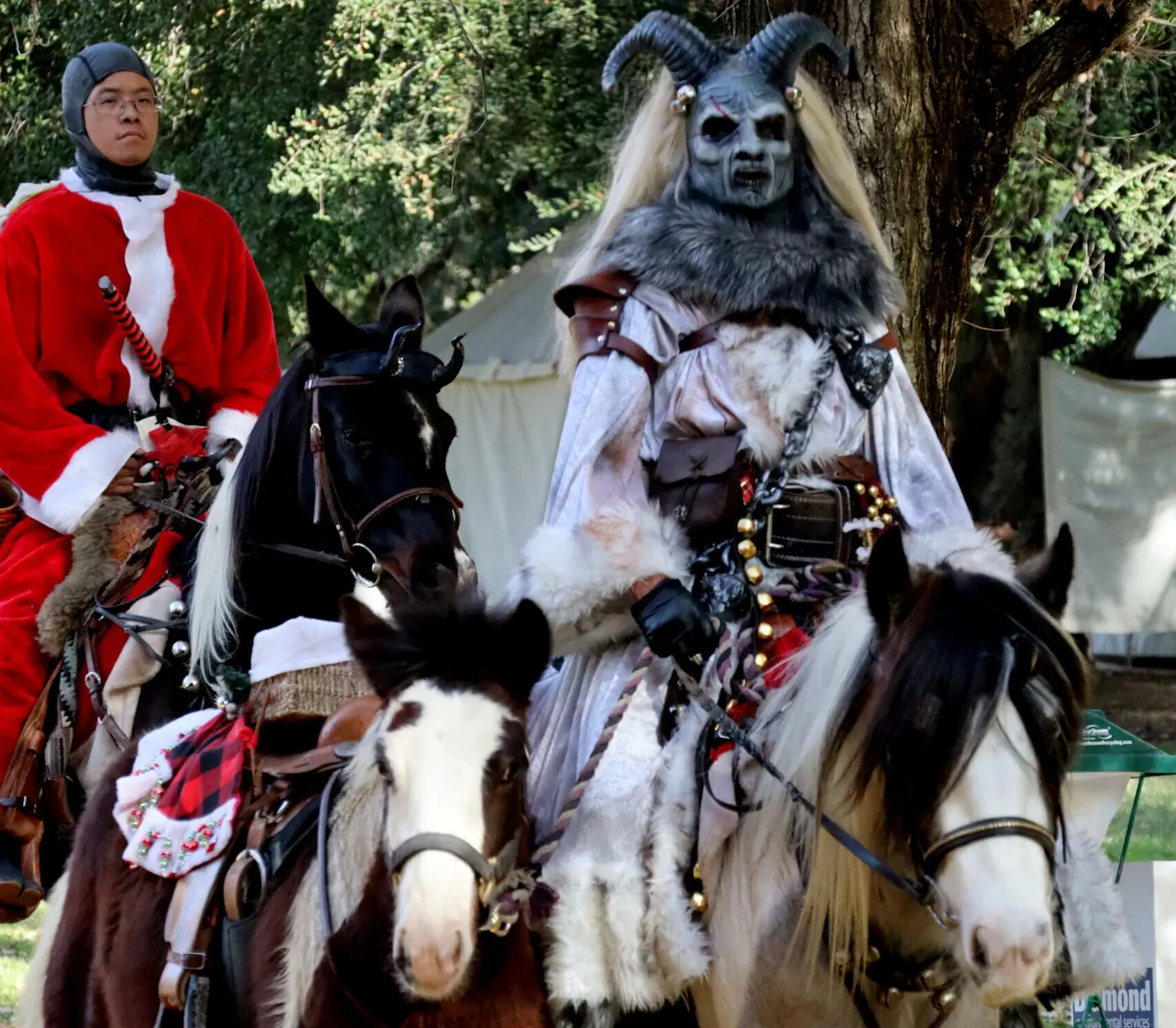 St. Nicholas in red and Krampus in horns and fur ride side by side on horseback