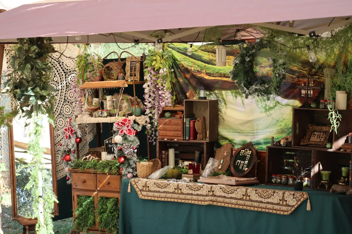 An apothecary booth dressed with greenery, wooden crates, bottles and a woodland backdrop