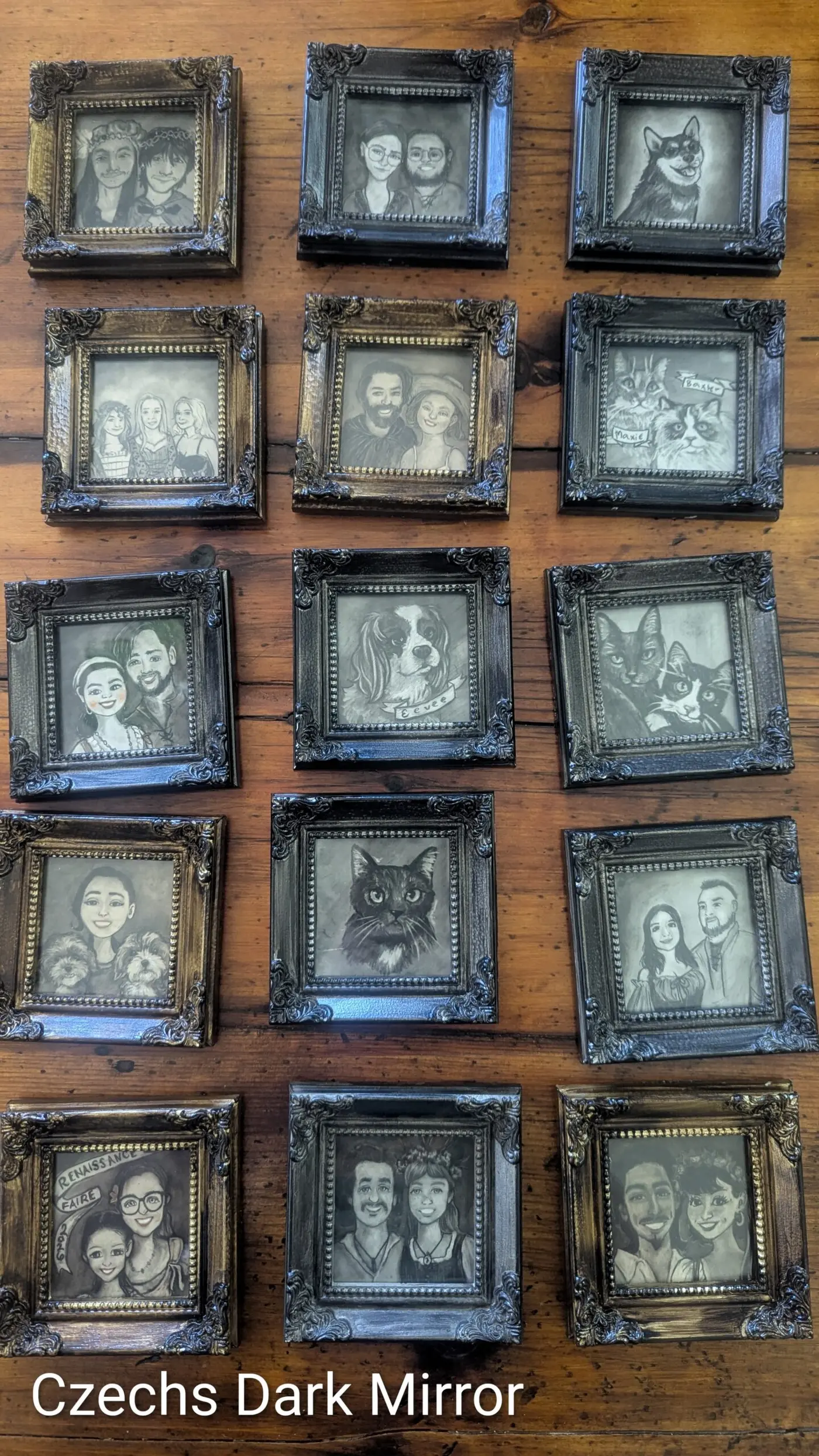 Framed pencil portraits displayed on a wooden board at the Czechs Dark Mirror booth