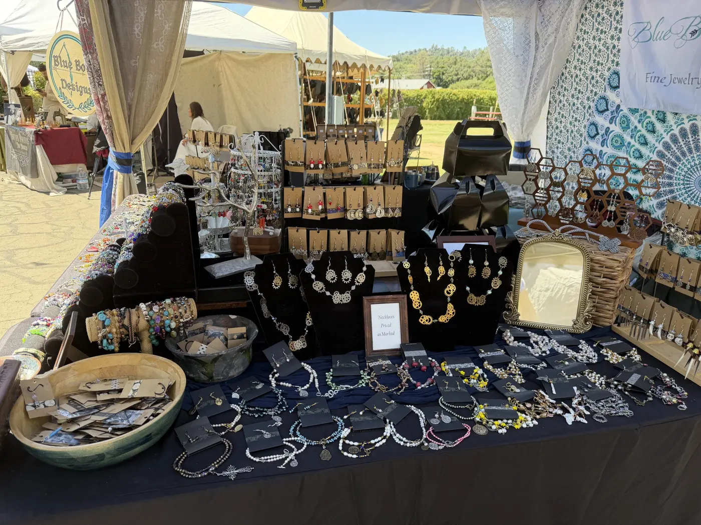 A jewelry booth with trays of bangles, rings and necklaces under a white canopy