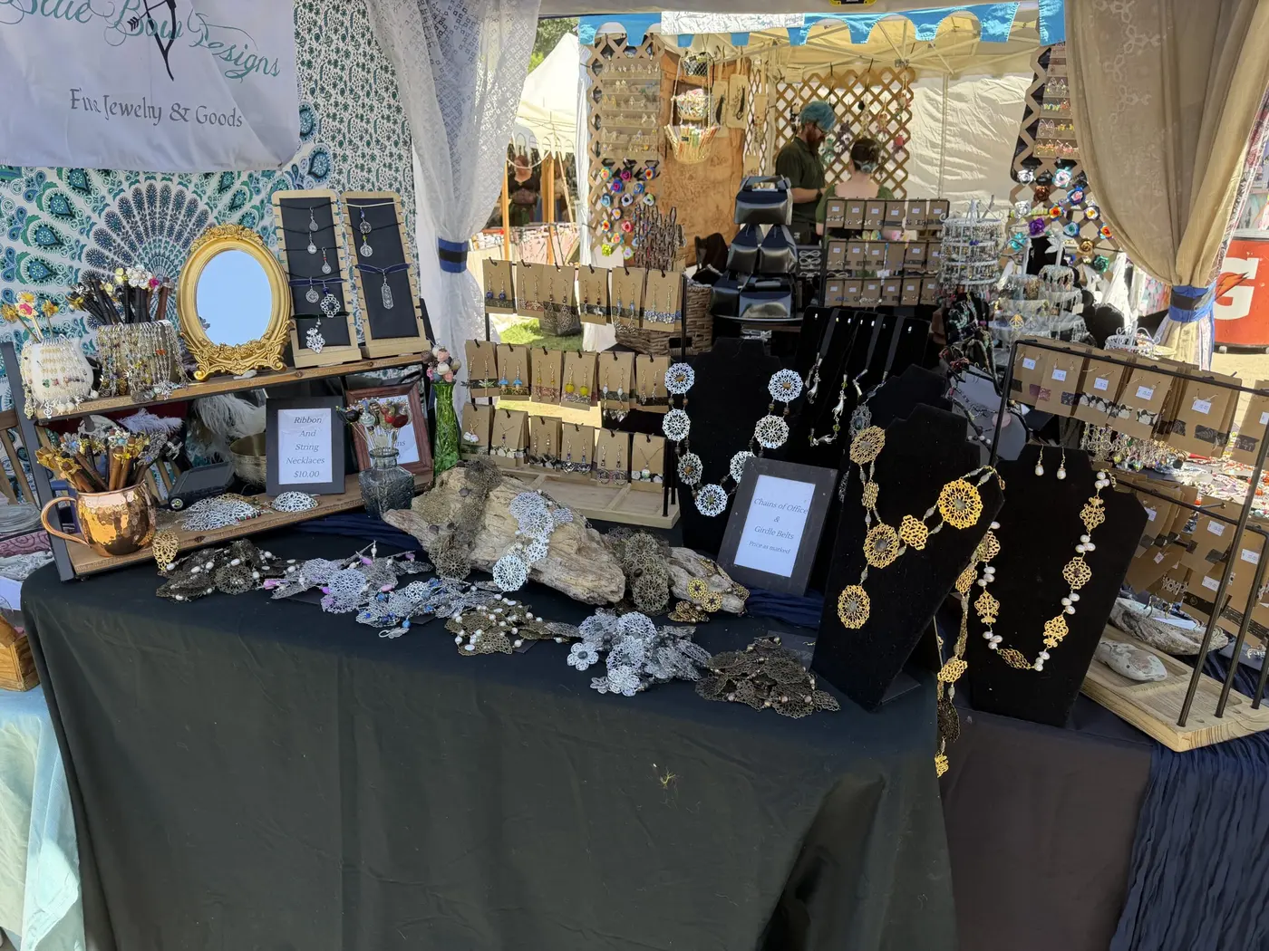 Necklaces, mirrors and pendants laid out on a black-draped jewelry table