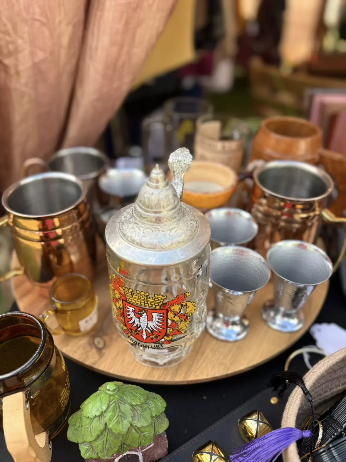 Pewter and copper tankards and a decorated stein on a wooden tray