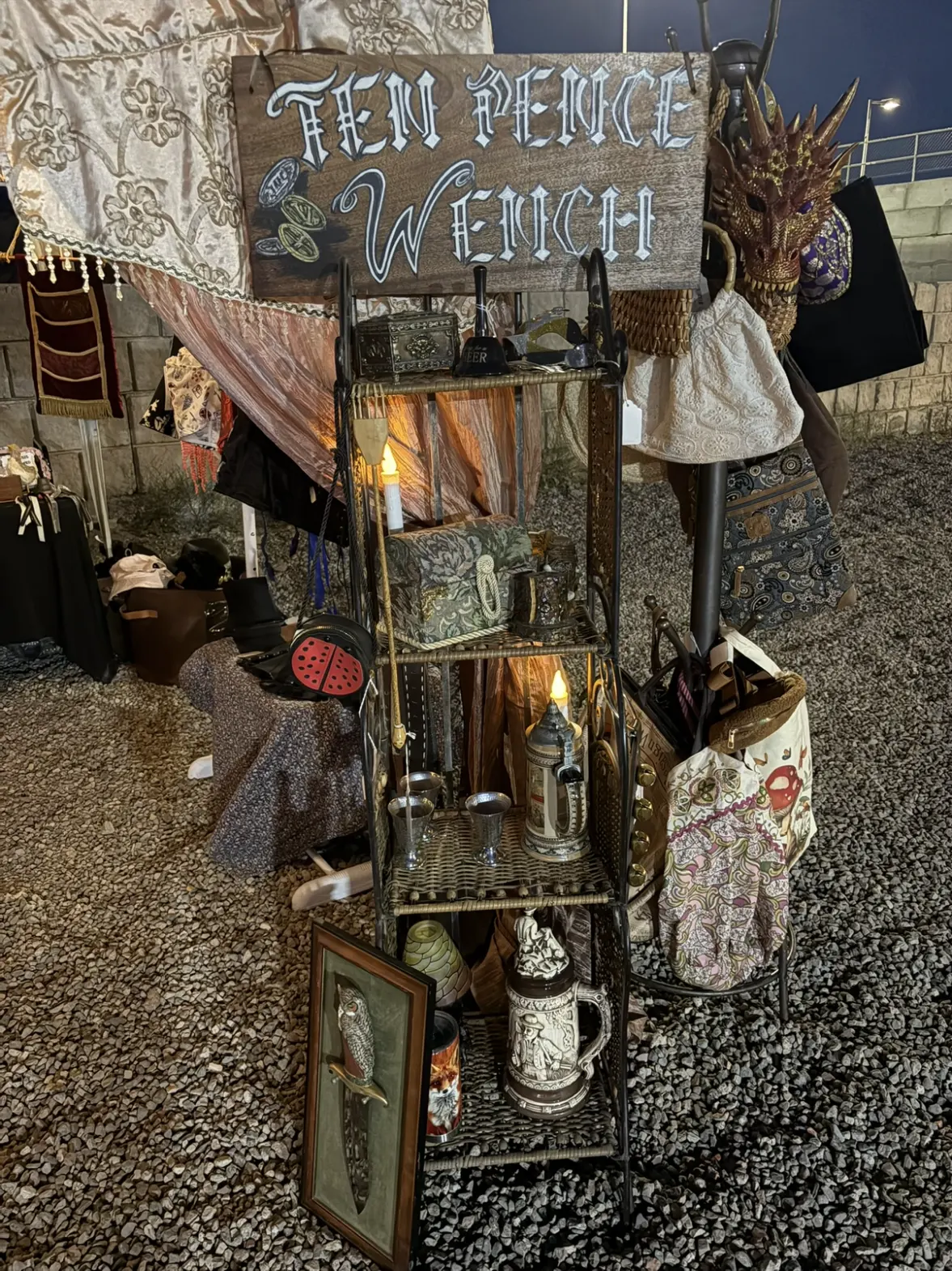 The Ten Pence Wench booth sign above lanterns, jugs and curios