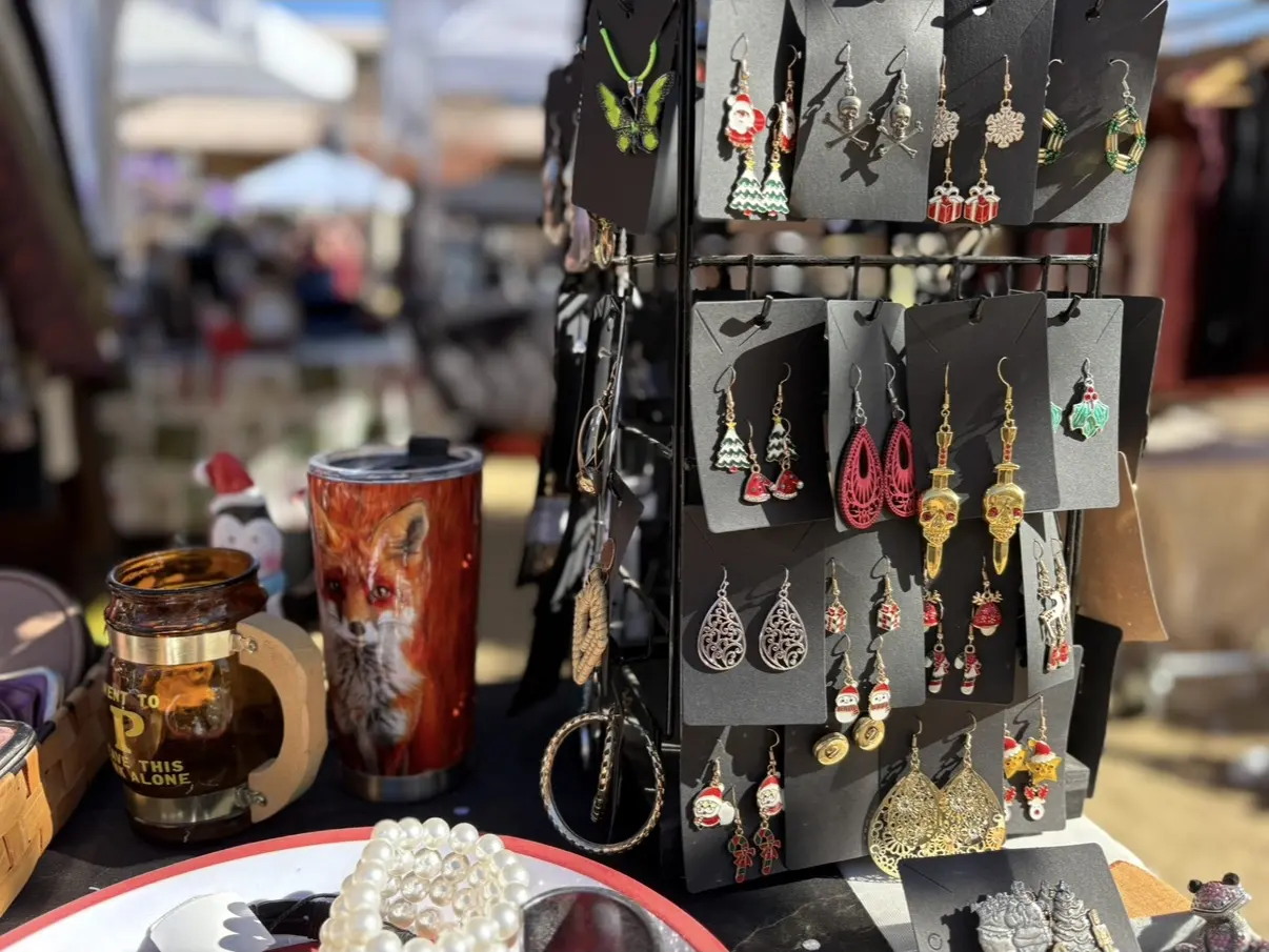 A rack of handmade earrings beside a fox-painted tumbler