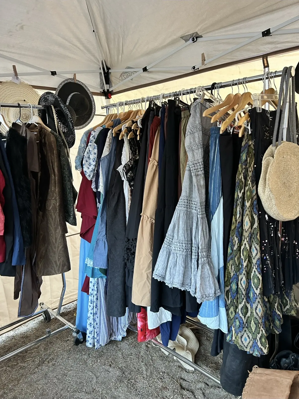 A rail of costume dresses and tunics with hats and a basket bag