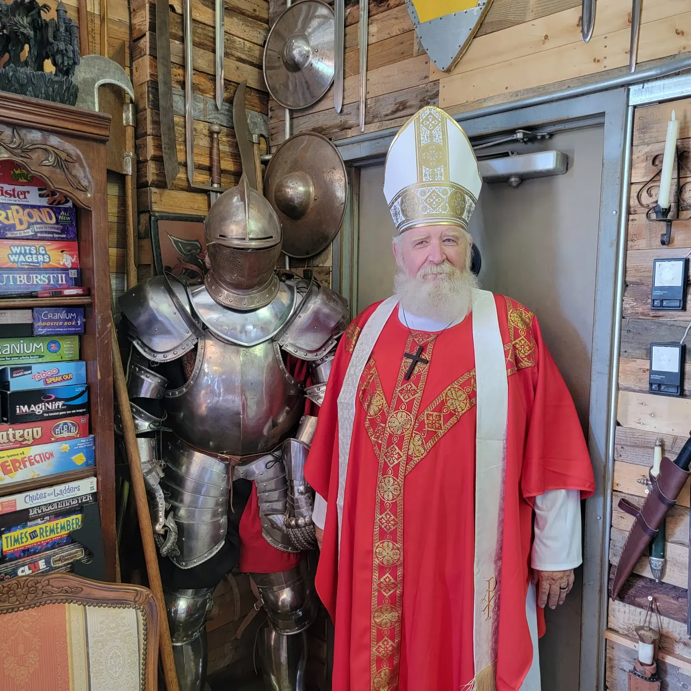 St. Nicholas in mitre and red vestments beside a full suit of plate armor