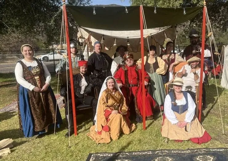 A company of costumed reenactors posing in front of their encampment